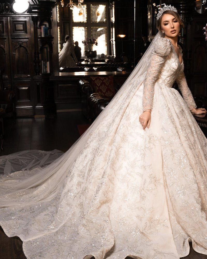 Bride in a beaded ball gown with a long cathedral train in a dark oak-panelled library